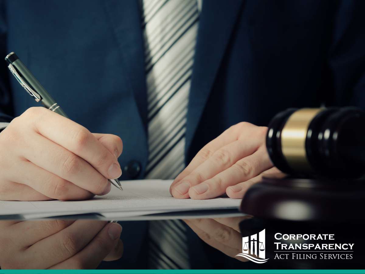 A professional signs a document next to a gavel, symbolizing legal compliance under the Corporate Transparency Act